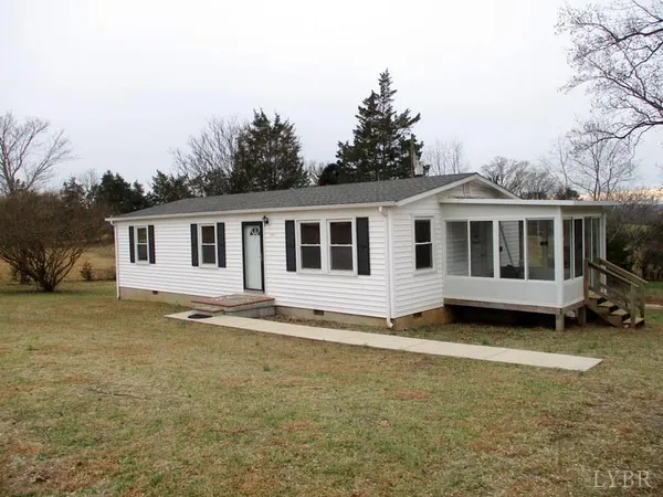 a view of a house with a yard and large trees