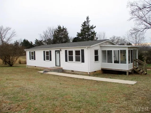 a view of a house with a yard and large trees
