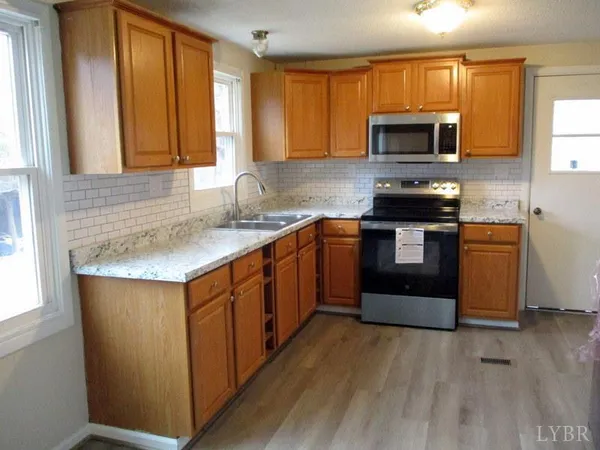 a kitchen with stainless steel appliances granite countertop wooden cabinets a stove a sink and a microwave