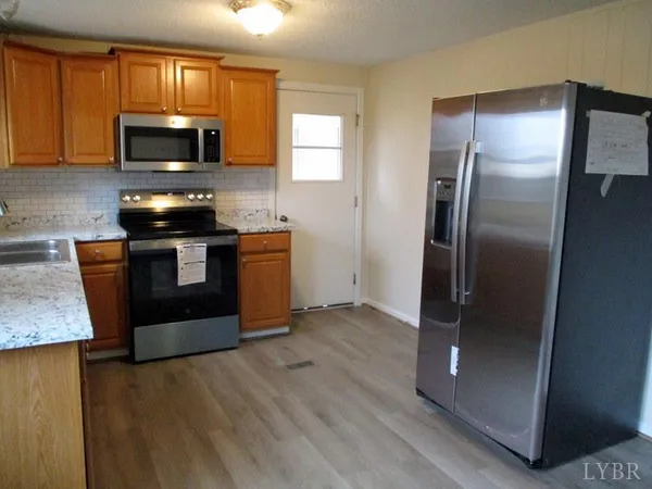 a kitchen with granite countertop a refrigerator stove and microwave