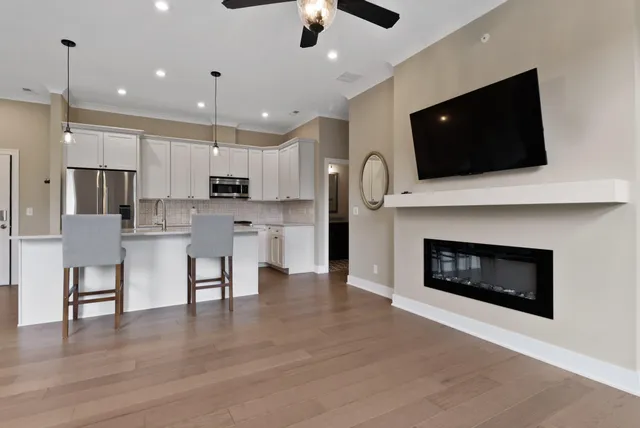 a open kitchen that has a fireplace a flat screen tv a island and stainless steel appliances