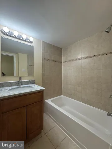 a bathroom with a granite countertop sink a mirror and a bathtub