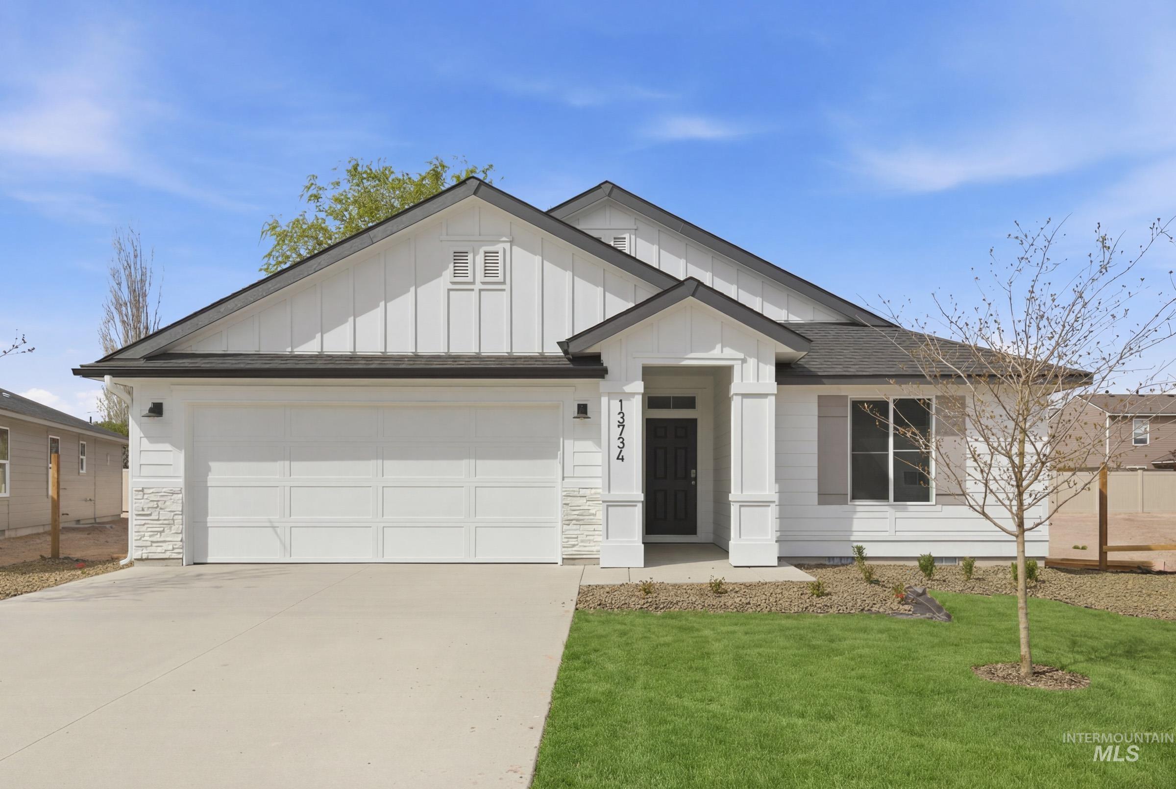 View of front of property featuring concrete driveway, a garage, a front yard, board and batten siding, and stone siding