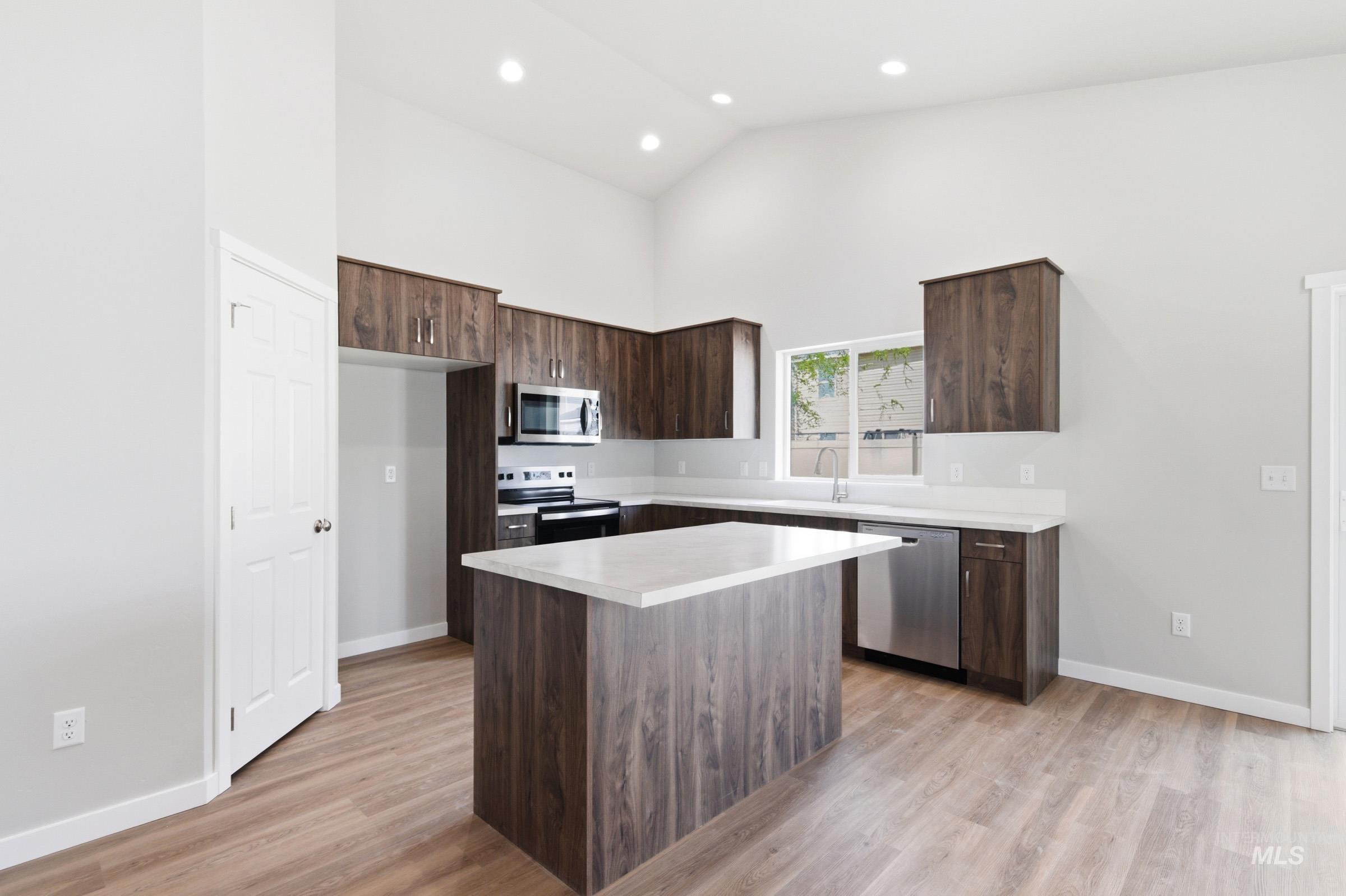 13734 Redway Court Caldwell, ID 83607 - Photo 3 of 20 Kitchen with dark wood finish cabinetry, light countertops, stainless steel appliances, light wood-style flooring, and vaulted ceiling