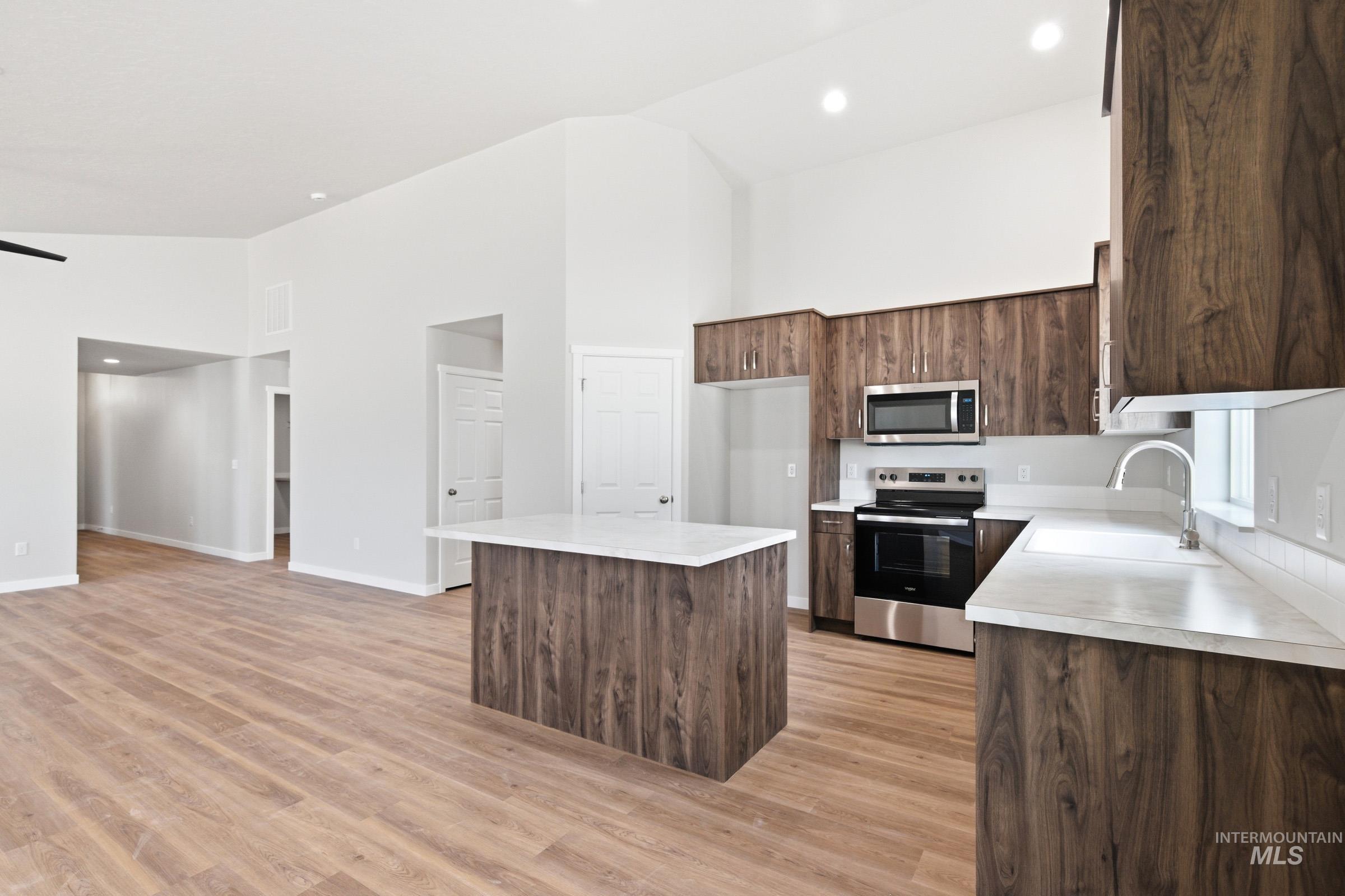 13734 Redway Court Caldwell, ID 83607 - Photo 5 of 20 Kitchen with stainless steel appliances, light countertops, a kitchen island, dark wood finish cabinetry, and light wood-type flooring
