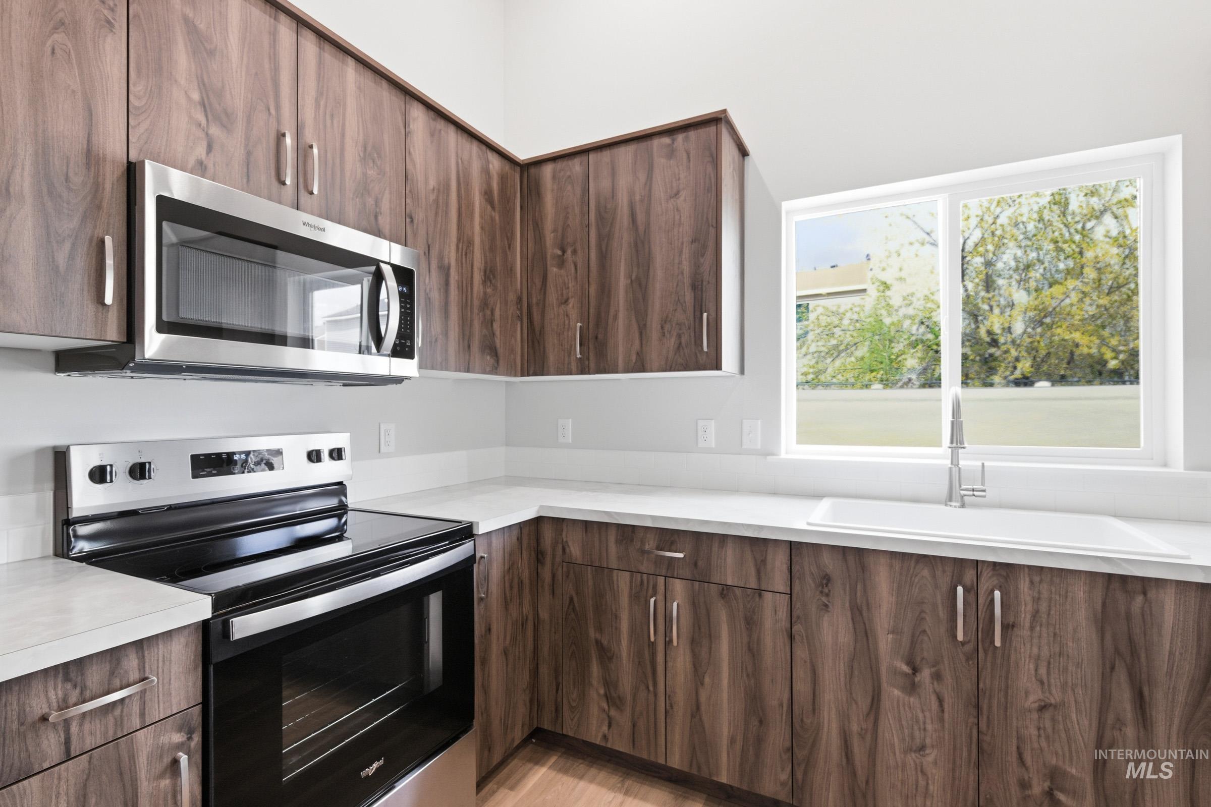 13734 Redway Court Caldwell, ID 83607 - Photo 7 of 20 Kitchen featuring stainless steel appliances, dark wood finish cabinets, light countertops, and modern cabinets