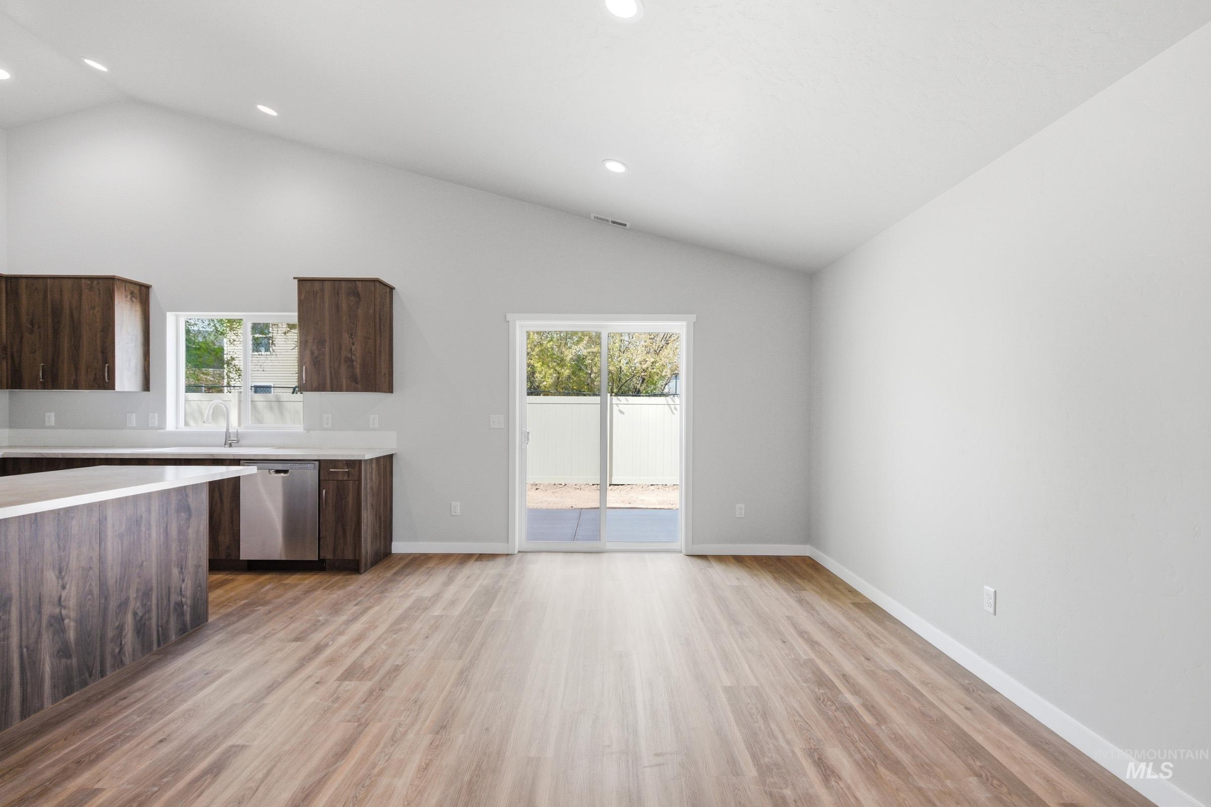 13734 Redway Court Caldwell, ID 83607 - Photo 8 of 20 Kitchen featuring dark wood finish cabinets, vaulted ceiling, light wood finished floors, dishwasher, and healthy amount of natural light