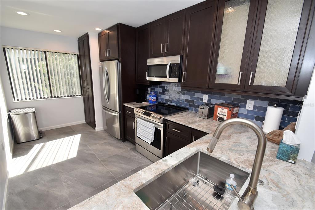 1508 Pelican Cove Road, Unit GR233 Sarasota, FL 34231 - Photo 18 of 37 a kitchen with stainless steel appliances granite countertop a refrigerator a stove a sink and a microwave