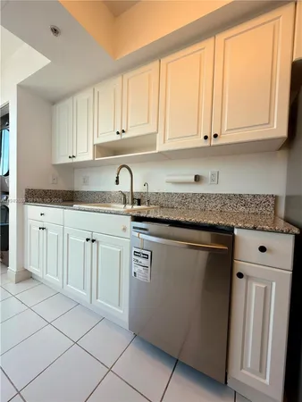 a kitchen with granite countertop white cabinets and sink