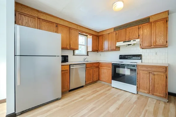 a kitchen with granite countertop appliances a sink cabinets and a window