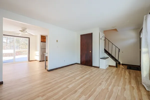 a view of an empty room with wooden floor and a window