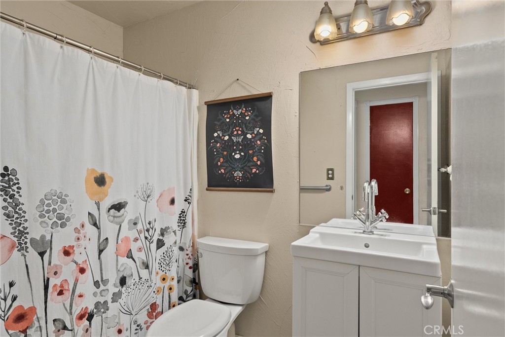 3030 Silverbell Road Chico, CA 95973 - Photo 25 of 42 a bathroom with a sink a mirror a toilet and shower curtain