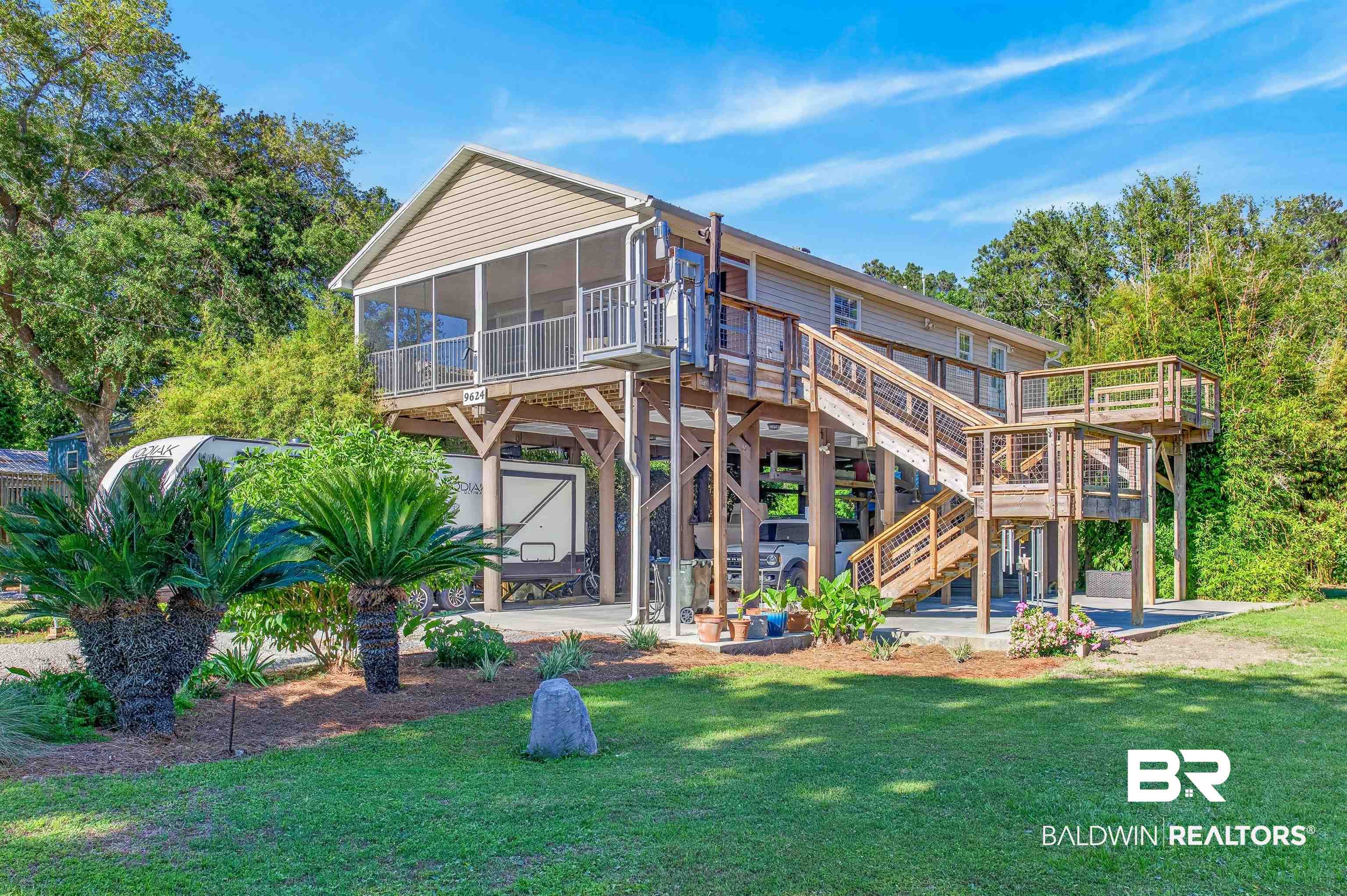 9624 North Bay Street Foley, AL 36535 - Photo 1 of 59 Elevated coastal property featuring a screened porch, multiple wooden deck areas, and a ground-level concrete pad