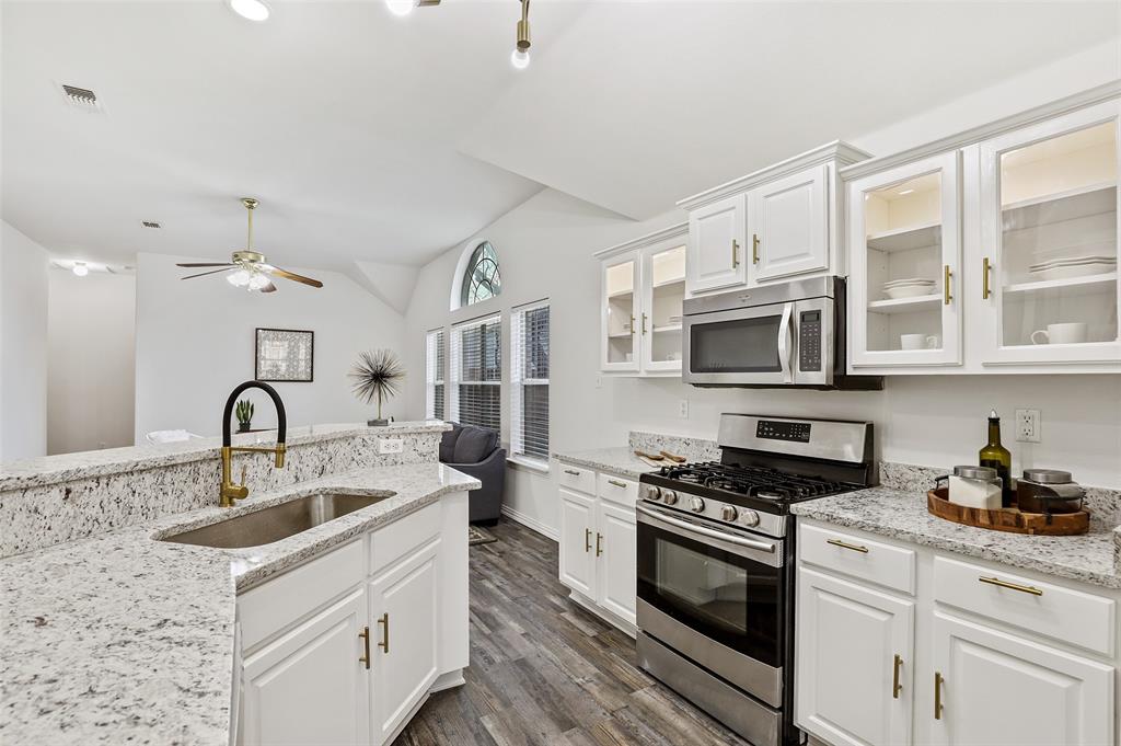 a kitchen with stainless steel appliances granite countertop a sink stove oven and white cabinets