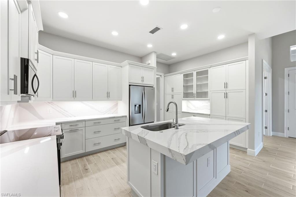 8937 Calypso Court Naples, FL 34113 - Photo 7 of 43 a kitchen with stainless steel appliances granite countertop a sink and a refrigerator