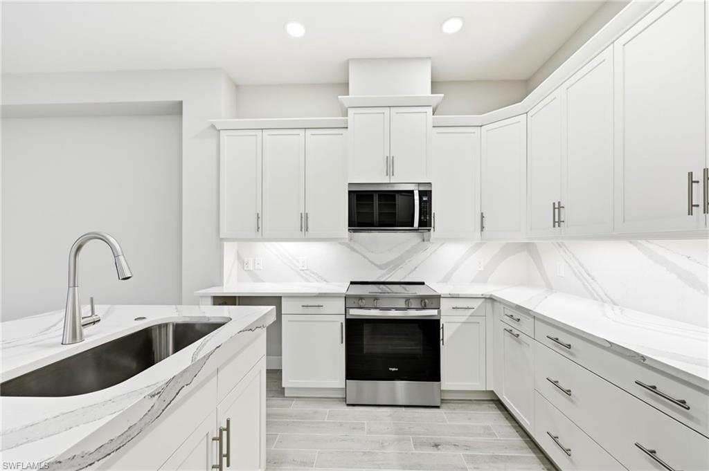 8937 Calypso Court Naples, FL 34113 - Photo 8 of 43 a kitchen with stainless steel appliances granite countertop a sink and a stove top oven with white countertops