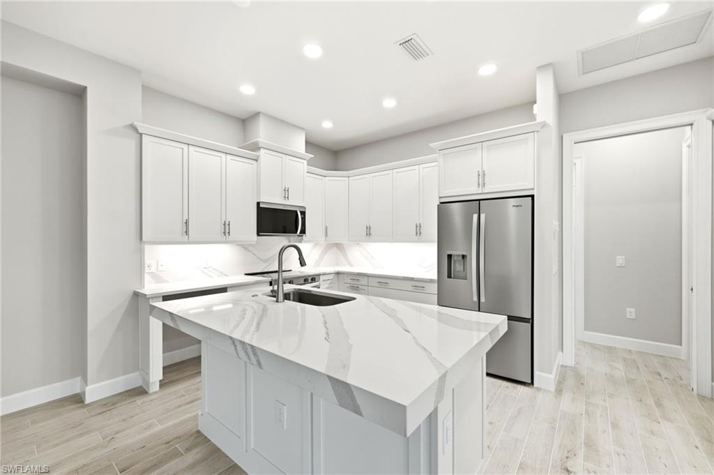 8937 Calypso Court Naples, FL 34113 - Photo 9 of 43 a kitchen with kitchen island a sink stove and refrigerator