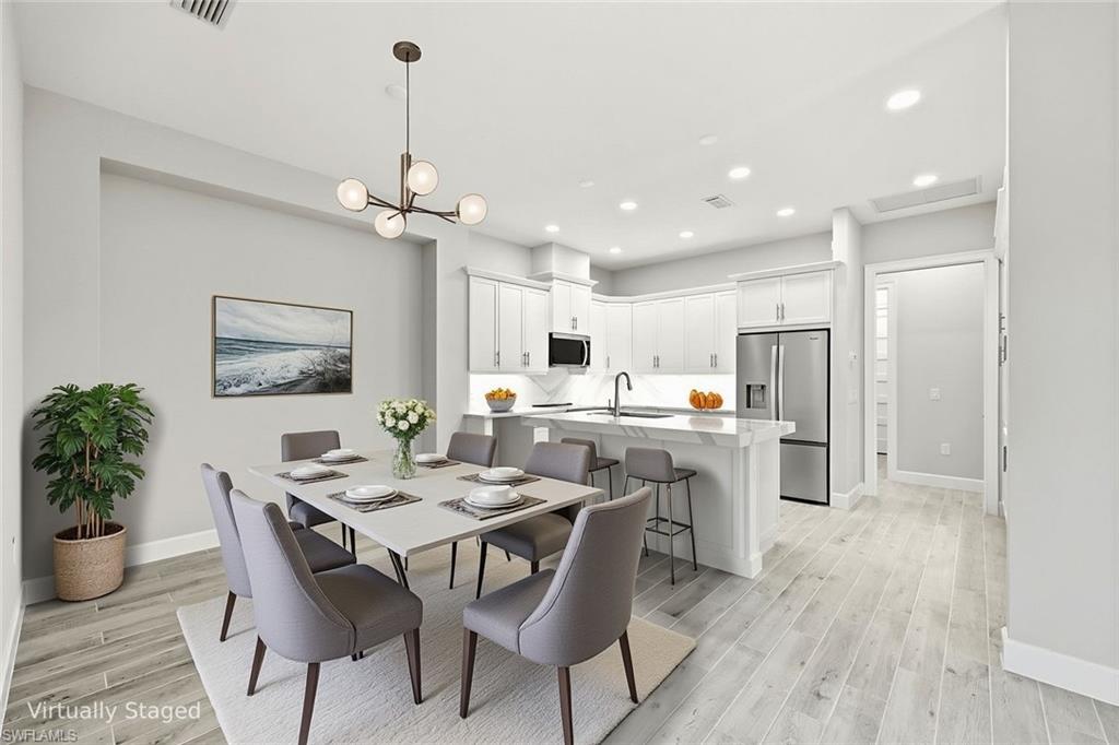8937 Calypso Court Naples, FL 34113 - Photo 10 of 43 a view of a dining room and livingroom with furniture wooden floor a chandelier