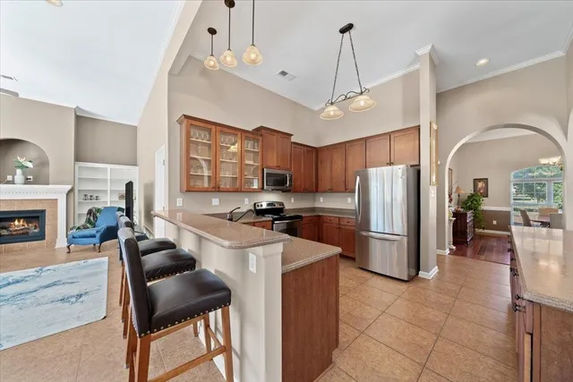 a kitchen with stainless steel appliances a refrigerator a stove a sink a dining table and chairs with wooden floor