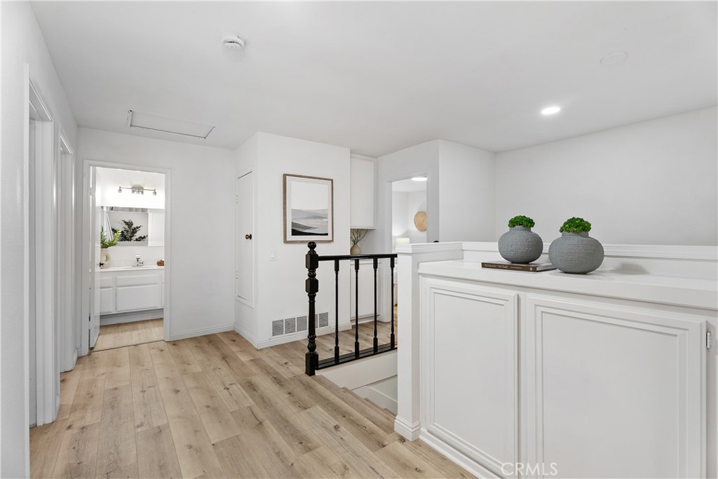 16 East Yale Loop, Unit 28 Irvine, CA 92604 - Photo 18 of 44 a kitchen with white cabinets and wooden floor