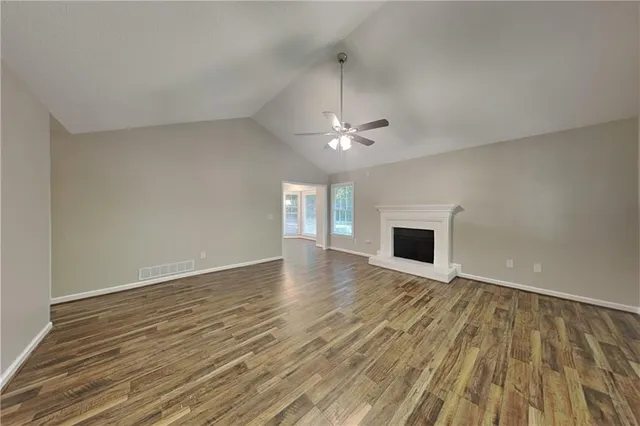 a view of an empty room with wooden floor and a fireplace