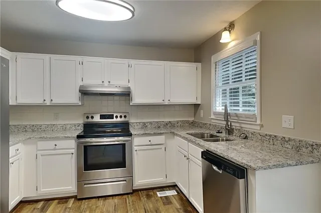 a kitchen with granite countertop white cabinets and white appliances