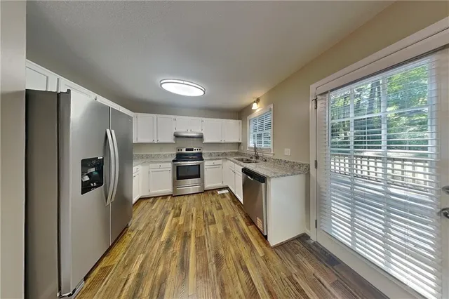 a kitchen with a refrigerator a stove top oven and white walls