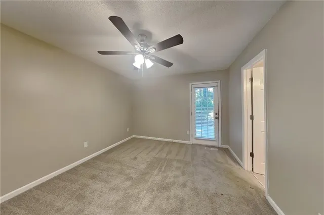 an empty room with chandelier fan and windows