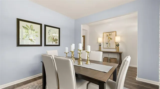 a kitchen with stainless steel appliances granite countertop a dining table chairs refrigerator and sink