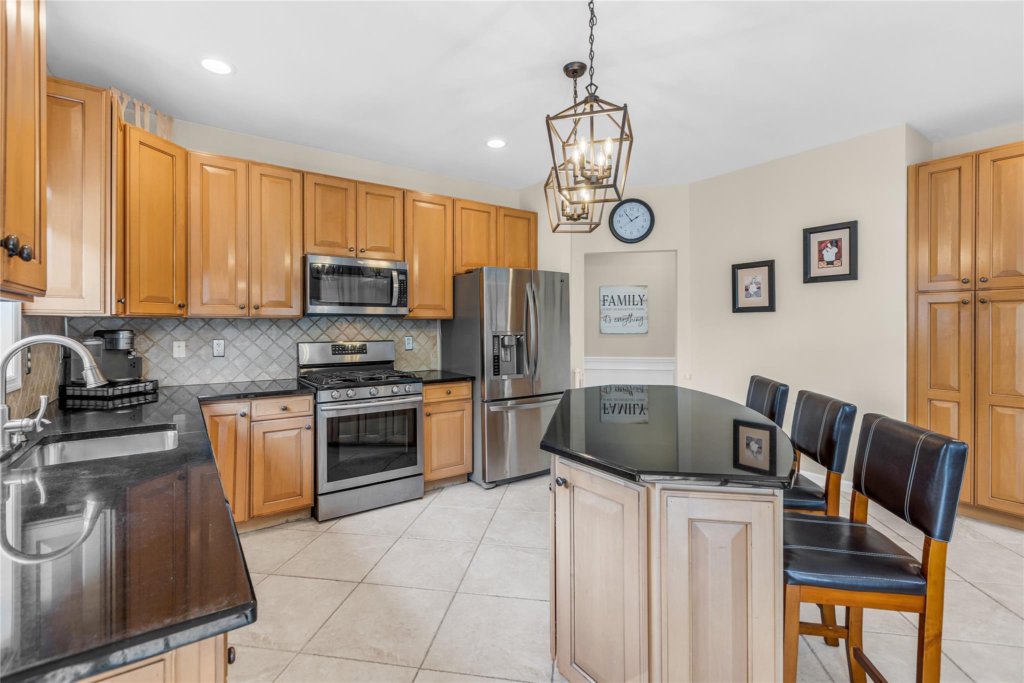 265 Hidden Acres Path Wading River, NY 11792 - Photo 12 of 46 Kitchen with stainless steel appliances, backsplash, light tile patterned flooring, a kitchen bar, and a kitchen island