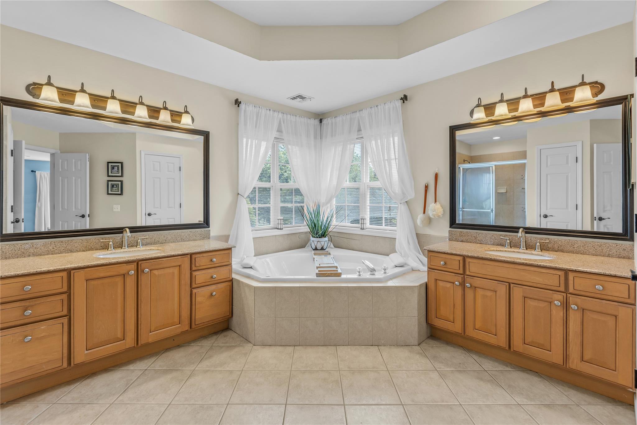 265 Hidden Acres Path Wading River, NY 11792 - Photo 17 of 46 Bathroom with two vanities, a shower stall, a garden tub, and tile patterned flooring