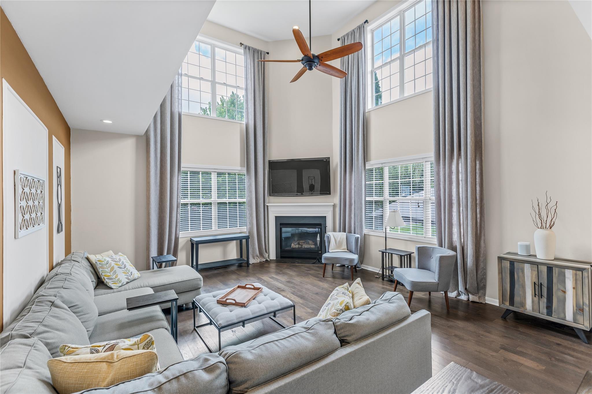 265 Hidden Acres Path Wading River, NY 11792 - Photo 9 of 46 Living room featuring plenty of natural light, a glass covered fireplace, wood finished floors, ceiling fan, and a towering ceiling