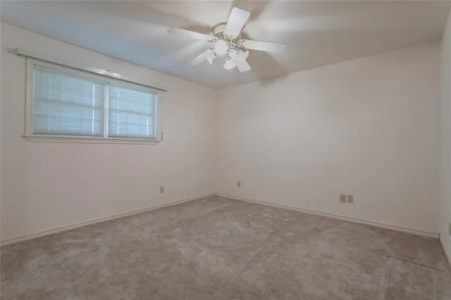 an empty room with a chandelier fan and windows