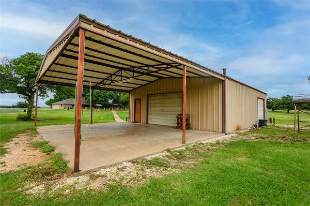 a backyard of a house with plants and large tree