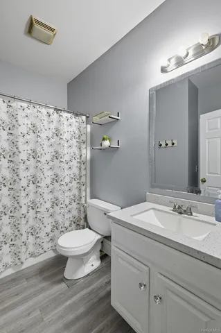 a bathroom with a granite countertop toilet a sink and a mirror
