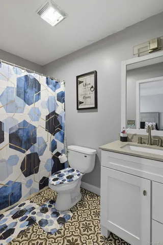 a bathroom with a granite countertop toilet a sink and a mirror