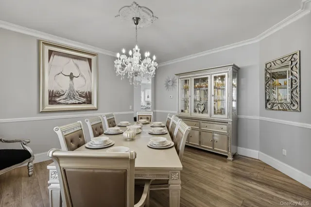 a dining room with wooden floor a chandelier a wooden table and chairs