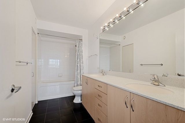 a spacious bathroom with a double vanity sink a toilet and a shower