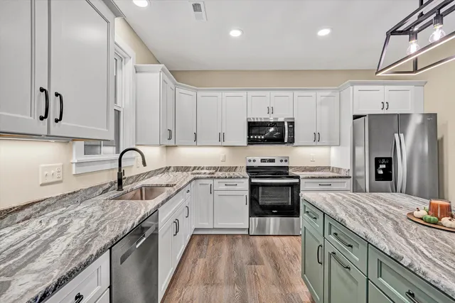 a kitchen with stainless steel appliances granite countertop a sink stove microwave and refrigerator