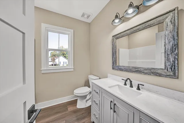 a bathroom with a granite countertop toilet a sink and mirror