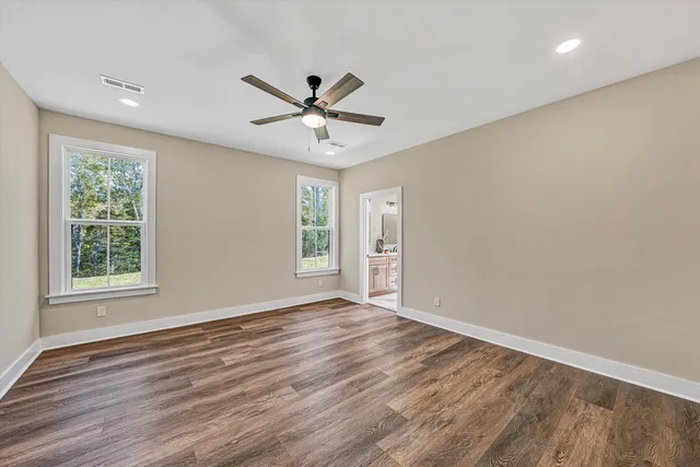 an empty room with wooden floor fan and windows