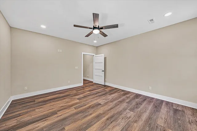 an empty room with a ceiling fan and wooden floor