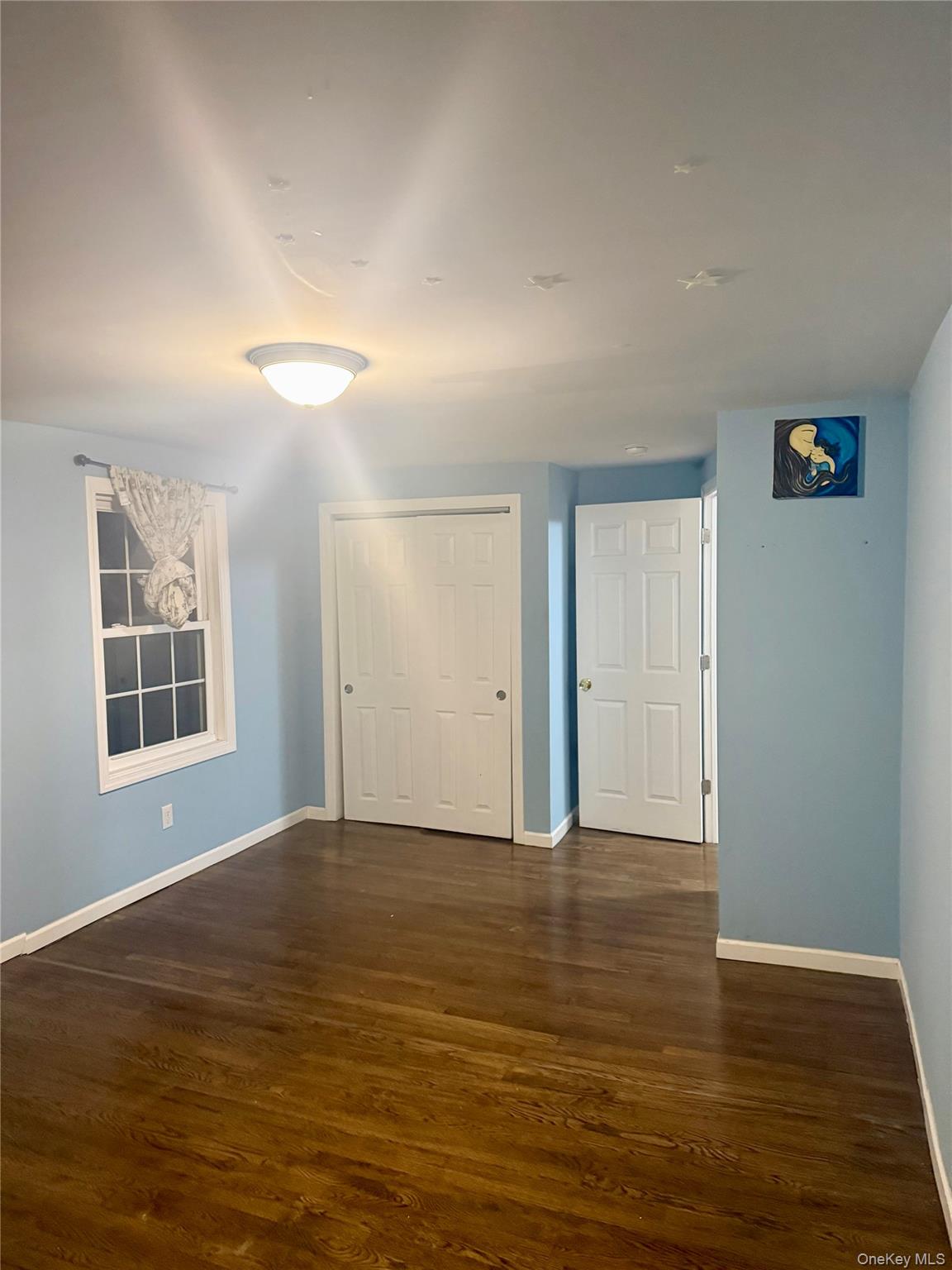 47 College Road Selden, NY 11784 - Photo 11 of 15 Unfurnished bedroom featuring dark wood-style flooring and a closet