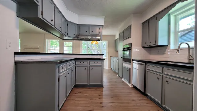 a kitchen with stainless steel appliances granite countertop a stove a sink dishwasher and a refrigerator with wooden cabinets