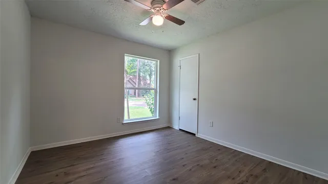 an empty room with wooden floor chandelier fan and windows