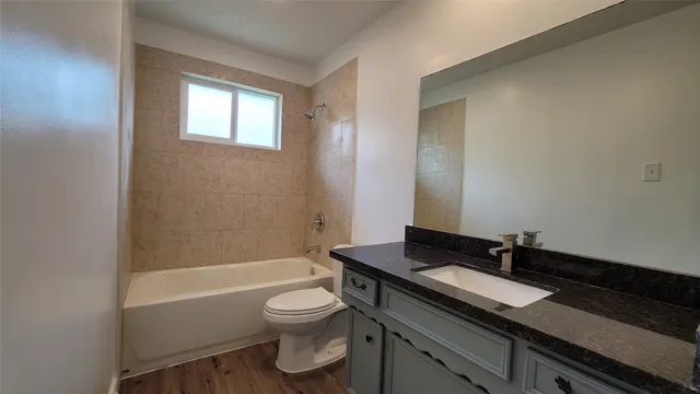 a bathroom with a granite countertop sink a toilet a mirror and bathtub