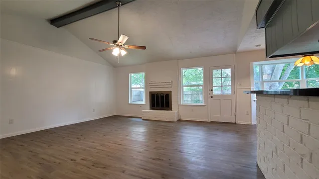 an empty room with wooden floor fireplace and windows