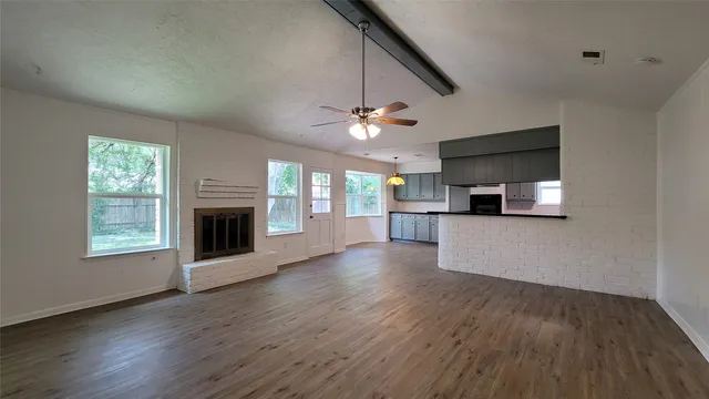 a view of empty room with wooden floor and a window
