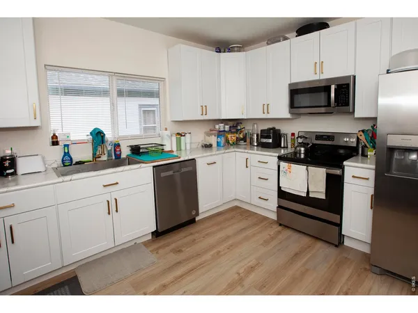 a kitchen with granite countertop a stove a sink dishwasher and a refrigerator with wooden floor