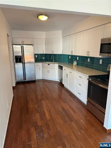 a kitchen with granite countertop a stove a sink and a refrigerator